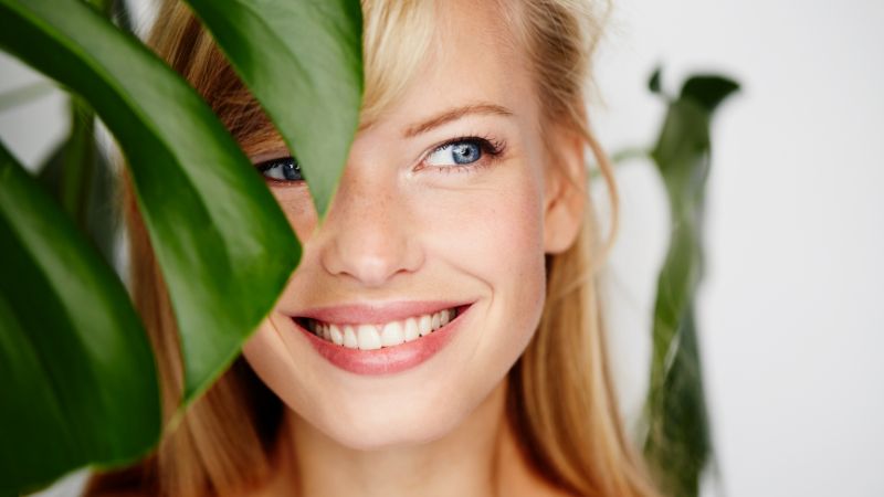 Smiling woman behind leaf